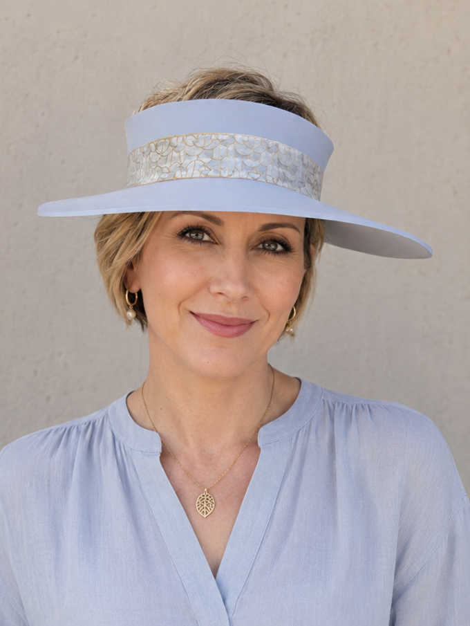 Woman wearing a light blue visor and matching blouse against a beige background