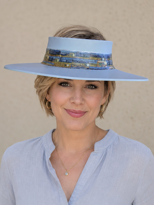 Woman wearing a light blue visor hat and matching shirt against a beige background