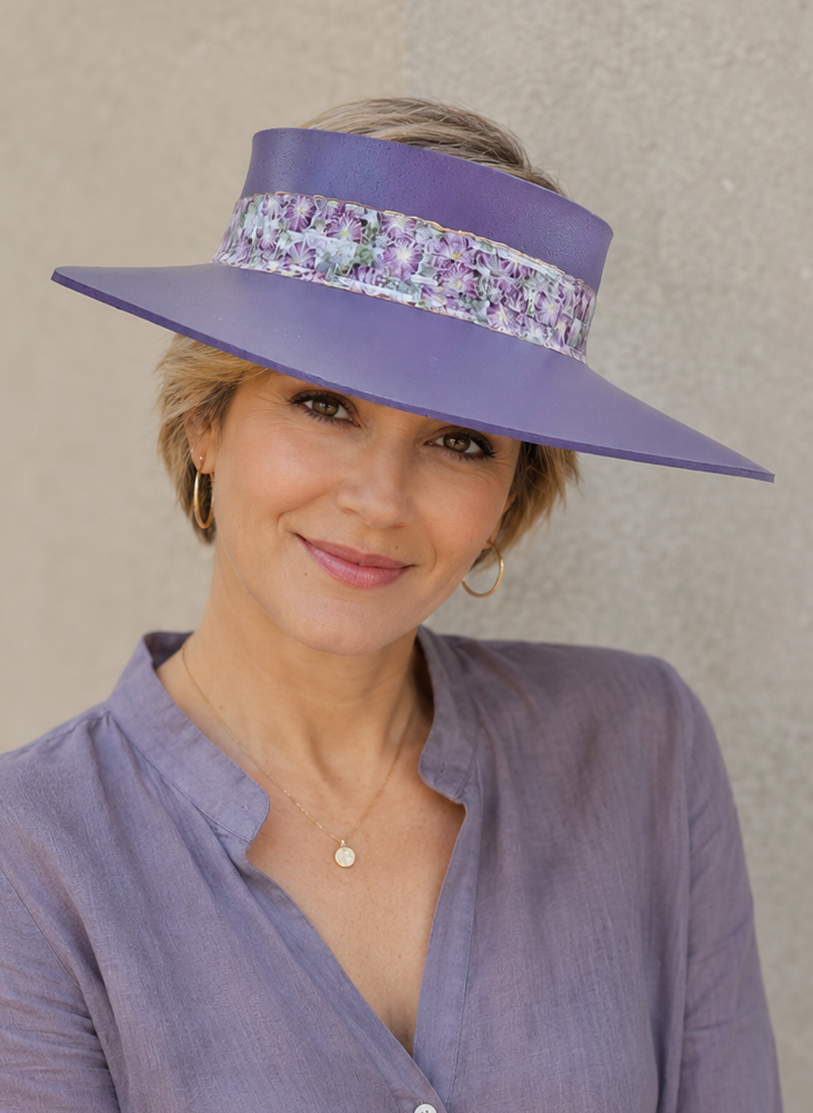 Woman wearing a purple sun visor hat against a beige background