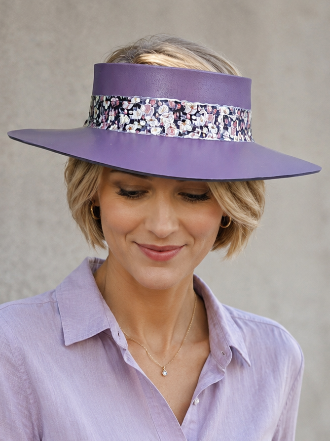 Woman wearing a purple hat with a decorative band and matching shirt against a plain background