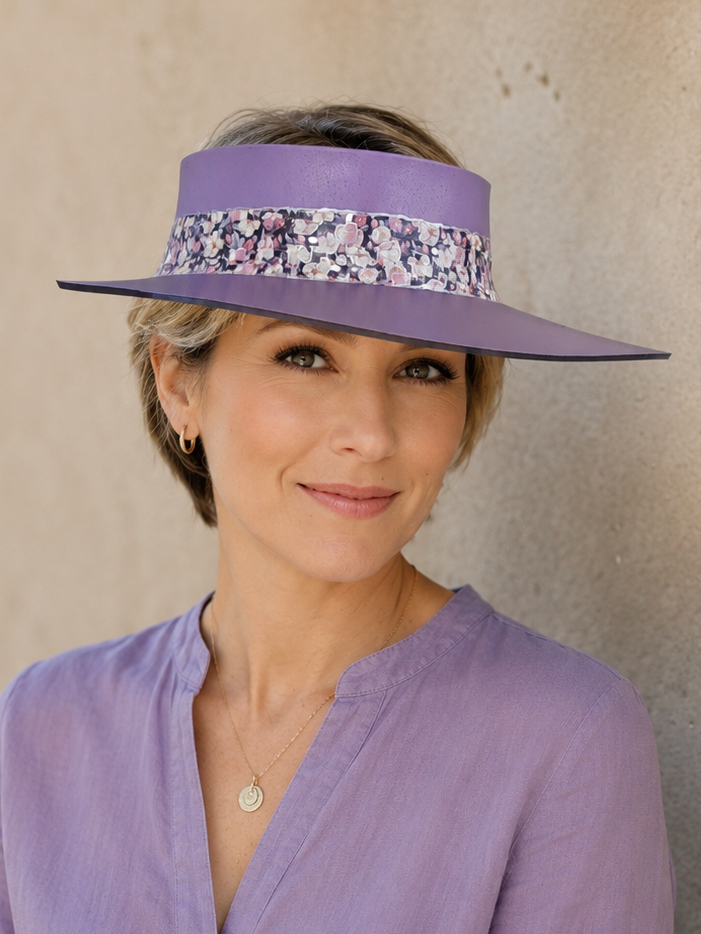 Woman wearing a purple visor and matching shirt against a beige wall