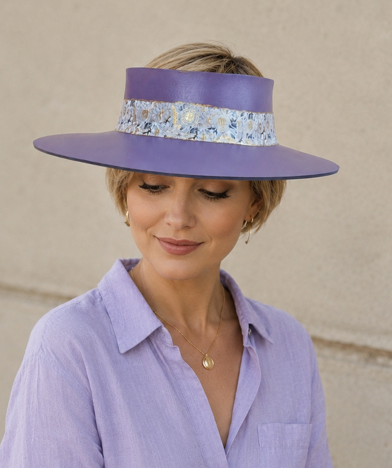 Woman wearing a purple hat with floral band and matching shirt against a beige wall.