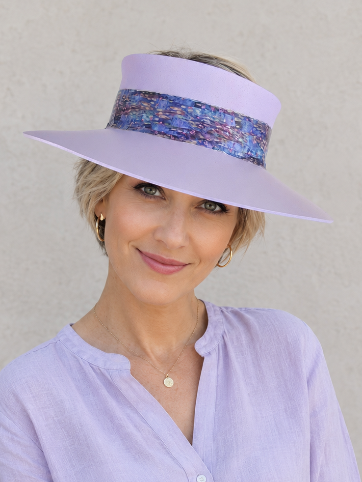 Woman wearing a lavender visor and shirt against a plain background