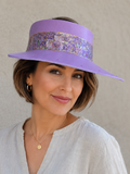 Woman wearing a purple hat with a decorative band against a neutral background