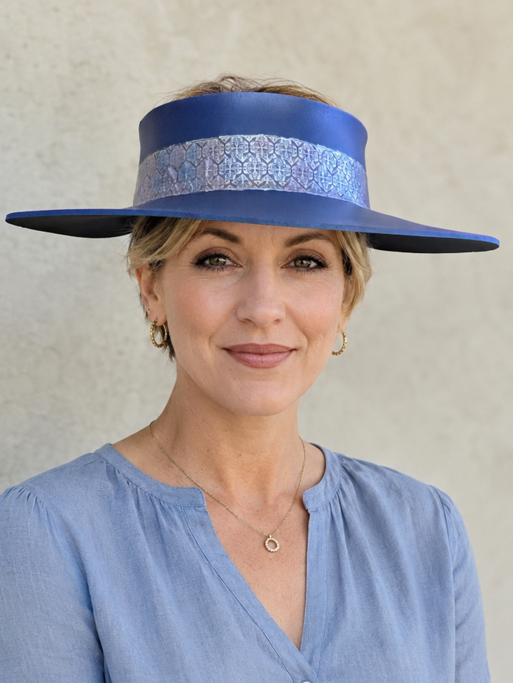Woman wearing a blue hat with a decorative band against a plain background