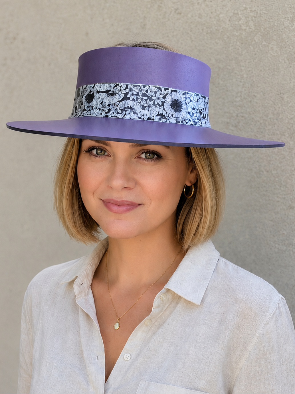 Woman wearing a purple hat with a floral band against a neutral background
