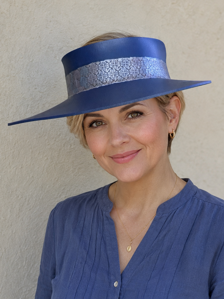 Woman wearing a blue hat and matching outfit against a beige wall