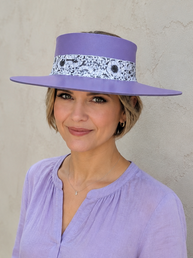 Woman wearing a purple hat with a decorative band against a beige wall