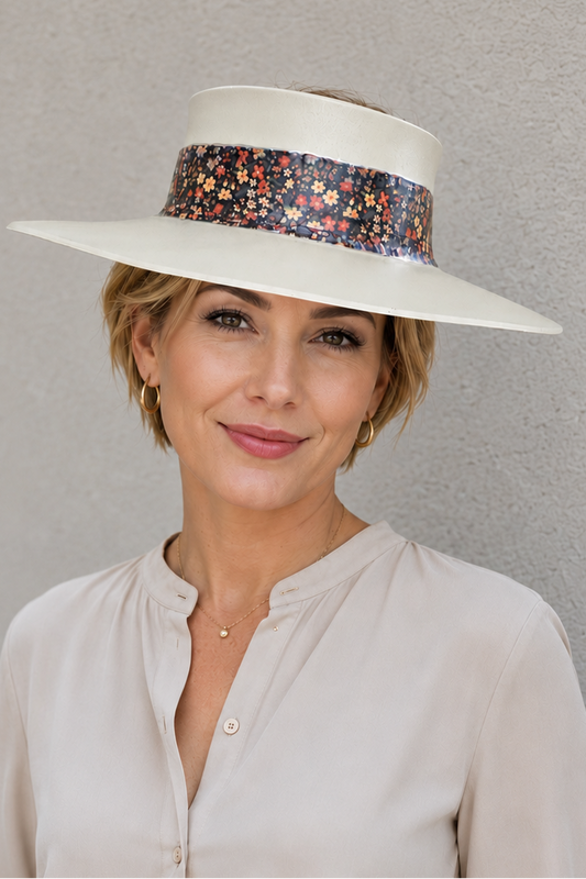 Woman wearing a white hat with a floral band against a gray background