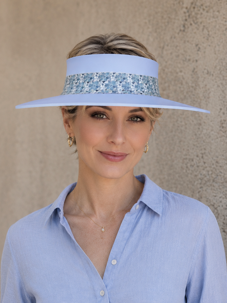 Woman wearing a light blue visor and shirt against a beige wall
