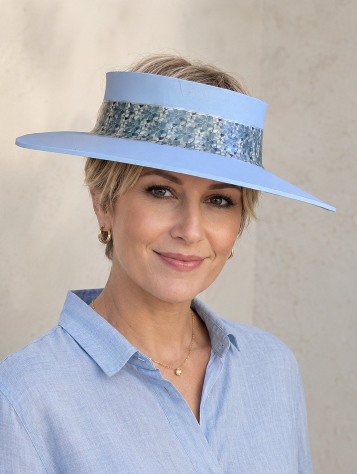 Woman wearing a light blue visor and matching shirt against a neutral background