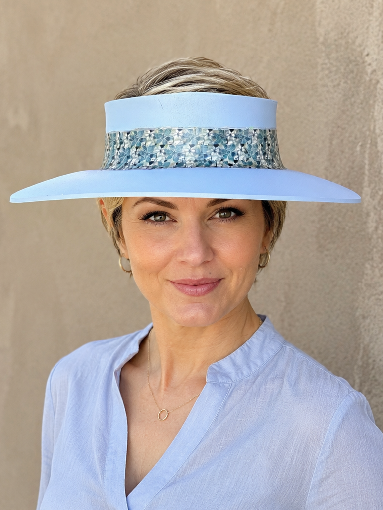 Woman wearing a light blue visor with a decorative band against a beige wall