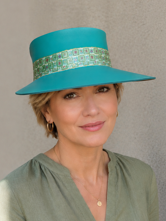 Woman wearing a teal hat with a patterned band against a plain background