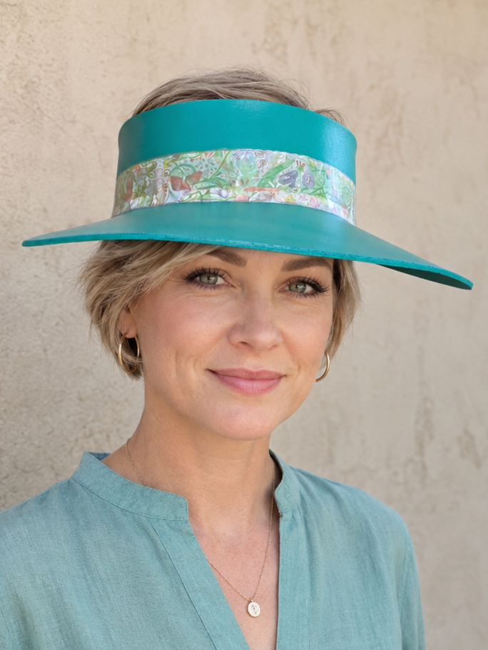 Woman wearing a teal visor hat against a beige wall