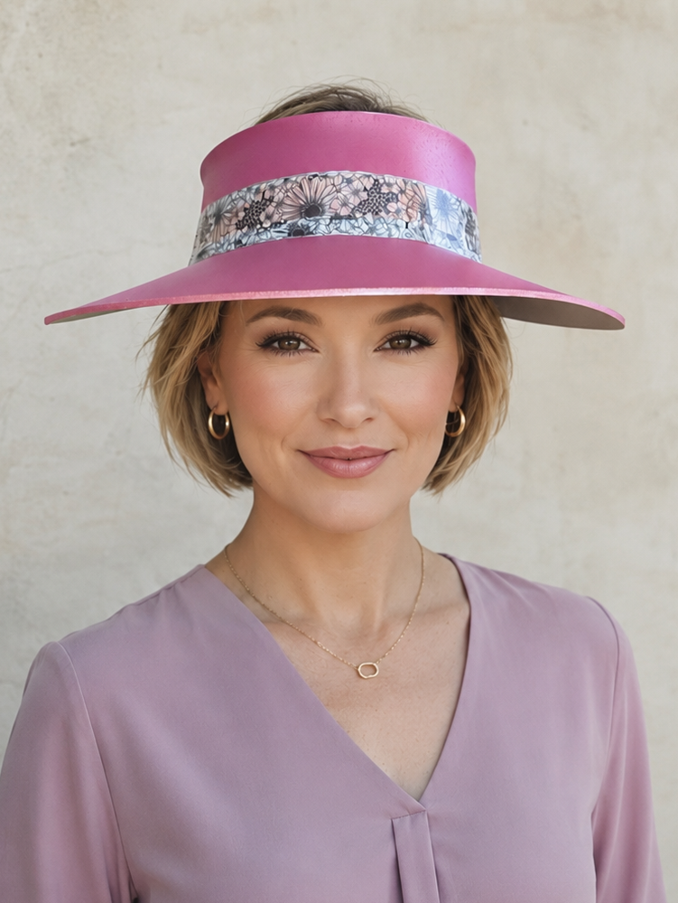 Woman wearing a pink visor with floral band and a matching blouse against a neutral background