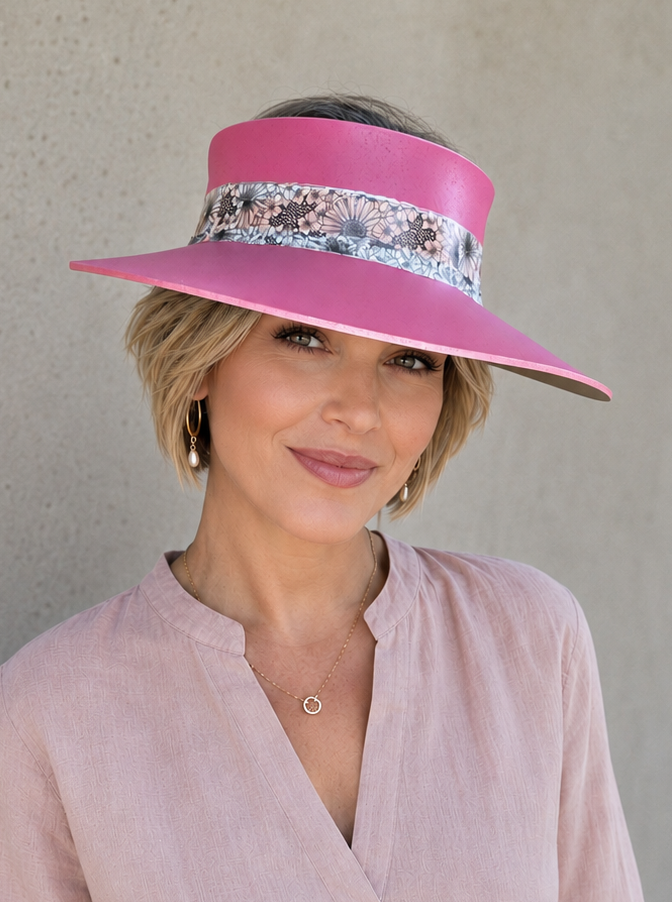 Woman wearing a pink visor with floral band against a plain background