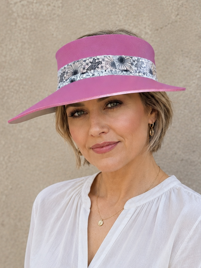 Woman wearing a white blouse and pink visor with floral band against a beige wall