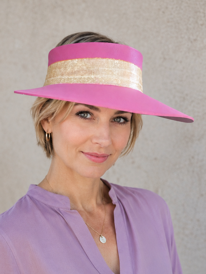 Woman wearing a pink visor with a beige band against a gray background