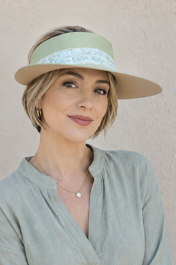 Woman wearing a light green visor and matching blouse against a beige background