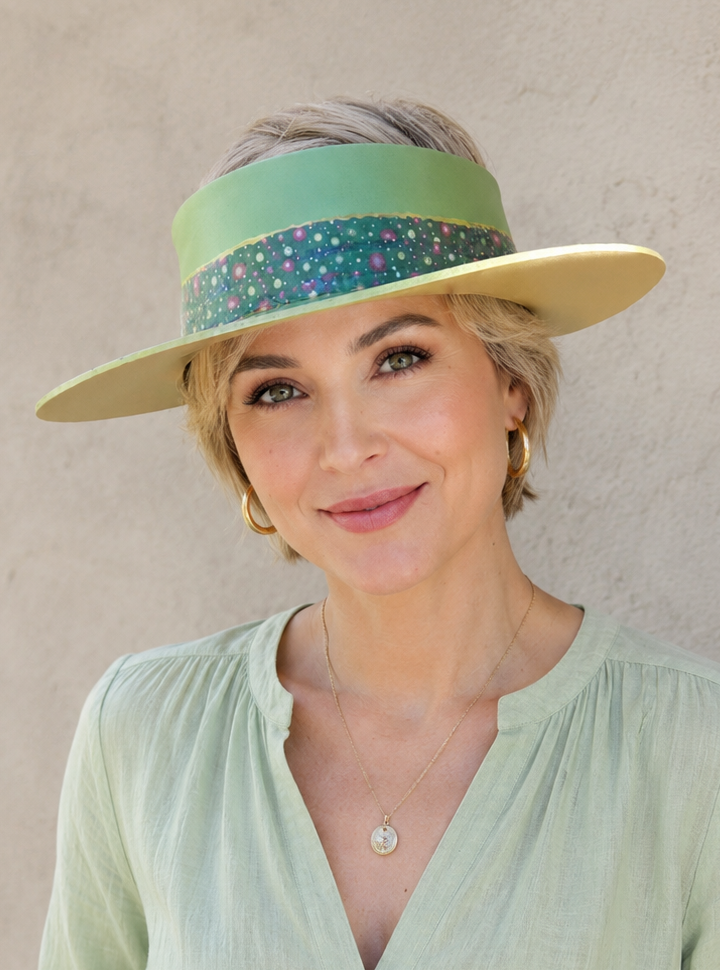 Woman wearing a light green visor and shirt against a neutral background
