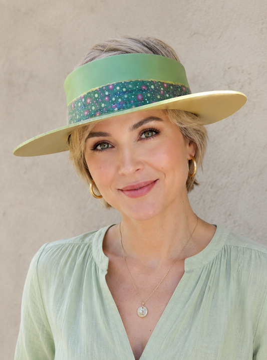 Woman wearing a light green visor and shirt against a neutral background