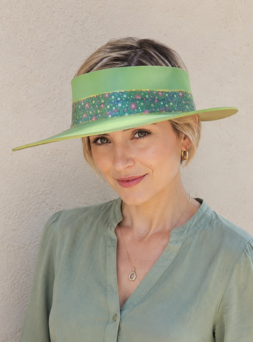 Woman wearing a green visor and light green shirt against a beige wall