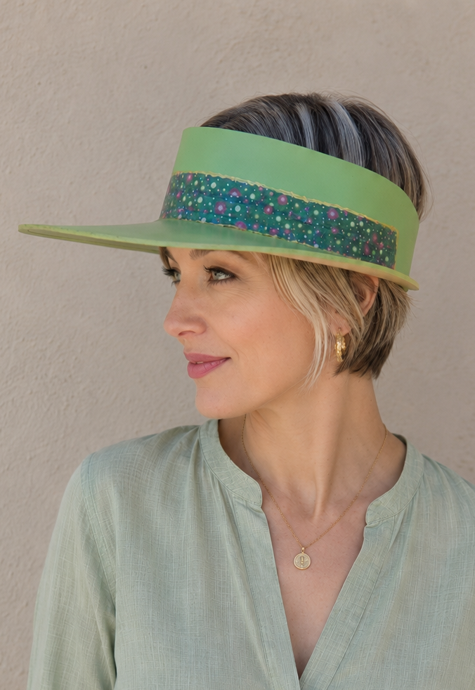 Woman wearing a green visor and light green shirt against a beige background