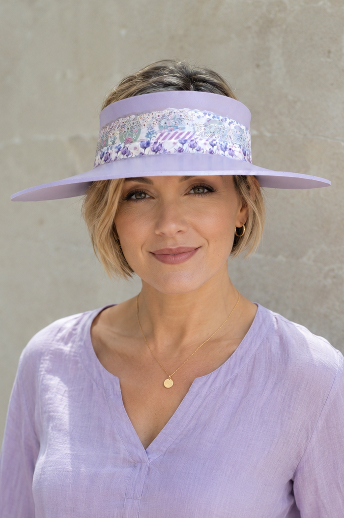 Woman wearing a light purple visor and shirt against a plain background