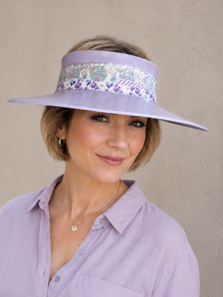 Woman wearing a lavender visor with floral band against a plain background
