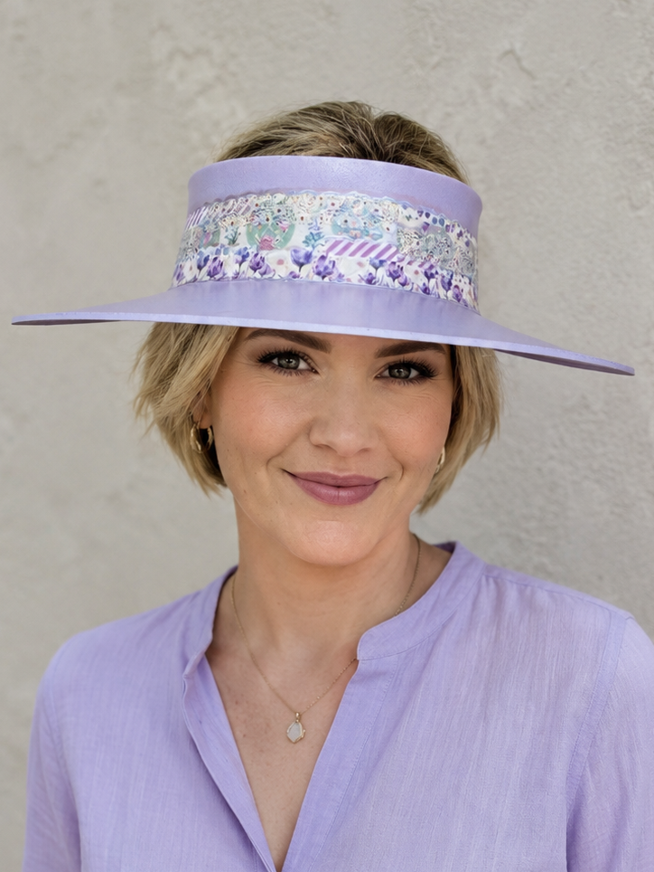 Woman wearing a purple visor with sequin embellishments against a plain background