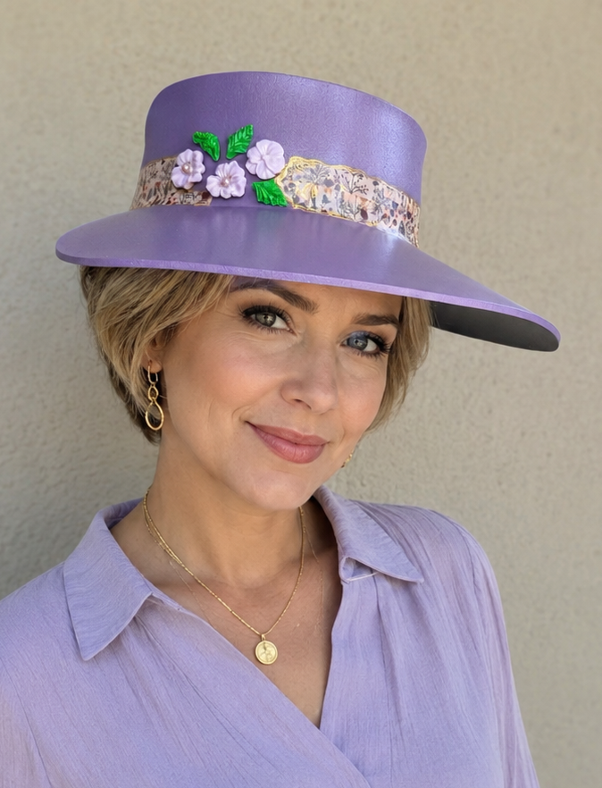 Woman wearing a purple hat with floral embellishments against a plain background
