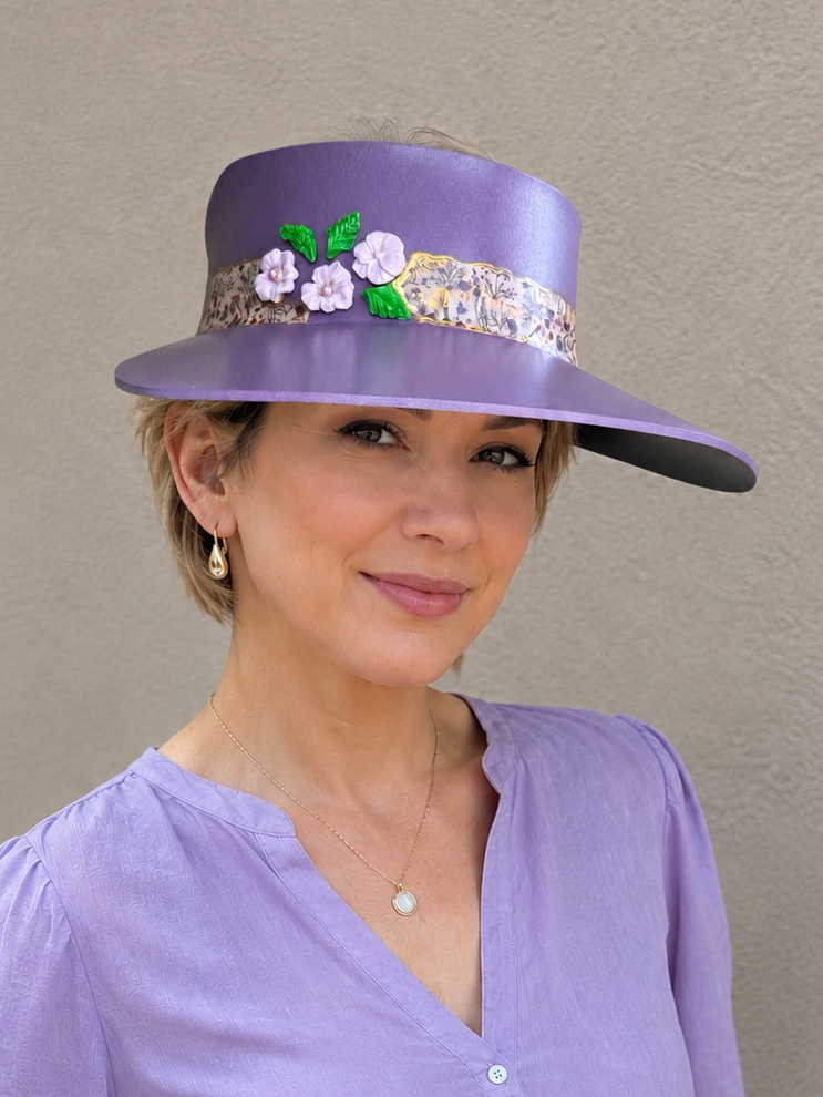Woman wearing a purple hat with floral embellishments against a plain background