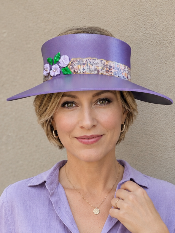 Woman wearing a purple hat with floral embellishments against a beige background