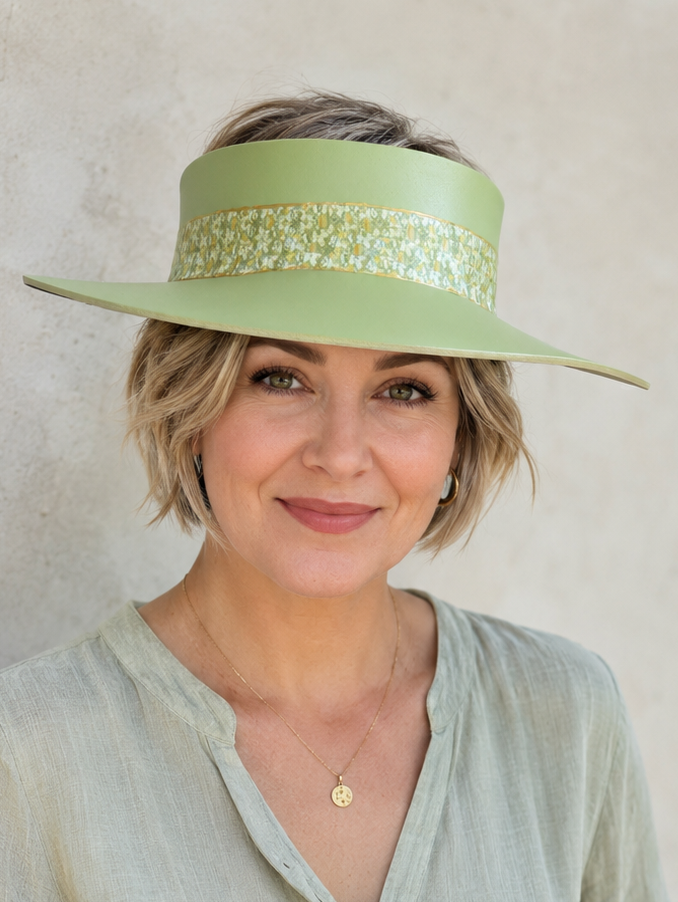Woman wearing a light green visor and matching shirt against a plain background