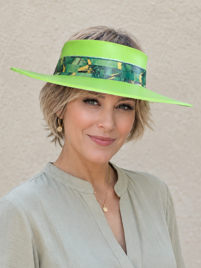 Woman wearing a bright green visor with a patterned band against a beige background