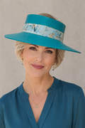 Woman wearing a teal blouse and hat with a floral band against a neutral background