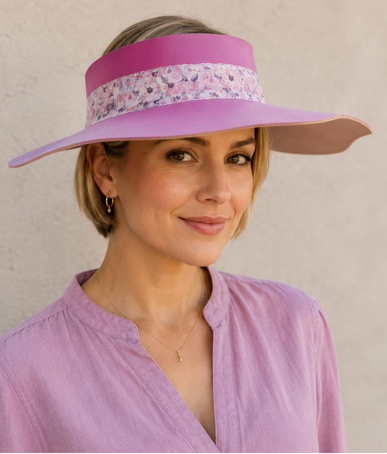 Woman wearing a purple visor and matching blouse against a beige wall