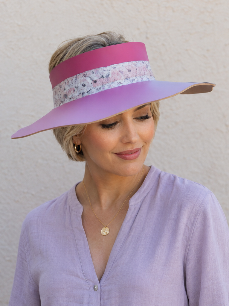 Woman wearing a pink visor and light purple shirt against a plain background