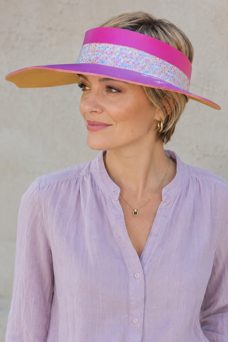 Woman wearing a colorful visor and light purple blouse against a plain background