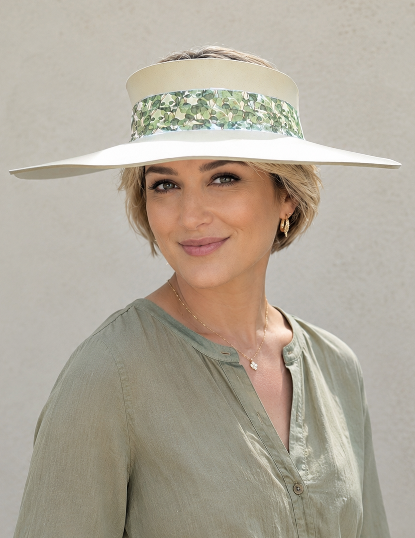 Woman wearing a wide-brimmed hat with a floral band against a plain background