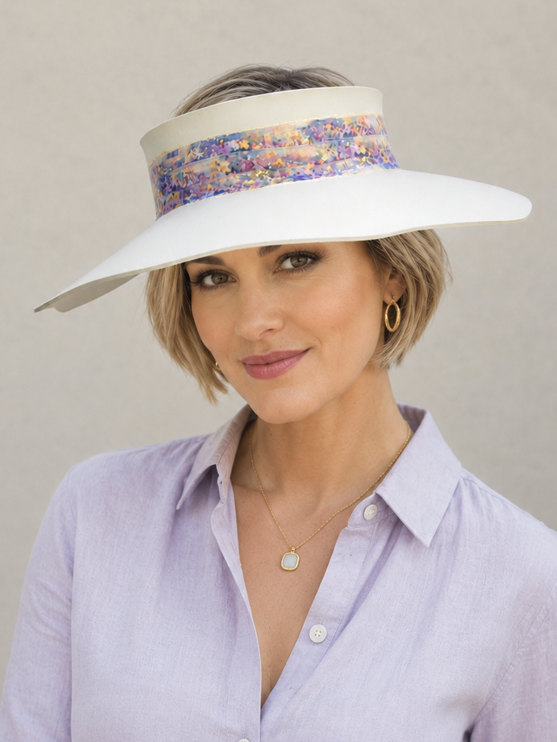 Woman wearing a wide-brimmed hat with a colorful band against a neutral background