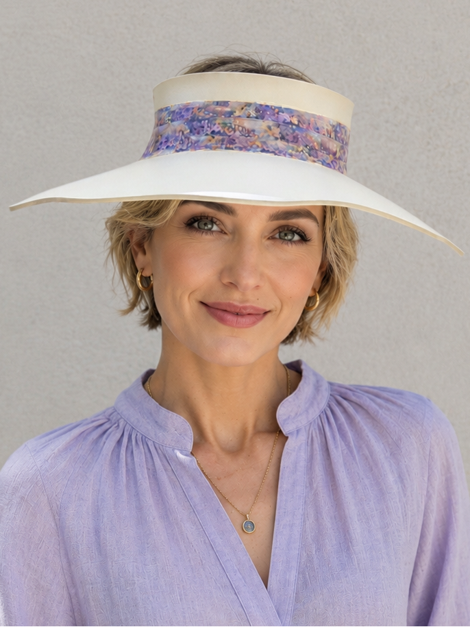 Woman wearing a white visor with a patterned band and a light purple shirt against a gray background