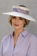 Woman wearing a wide-brimmed hat and light purple shirt against a gray wall