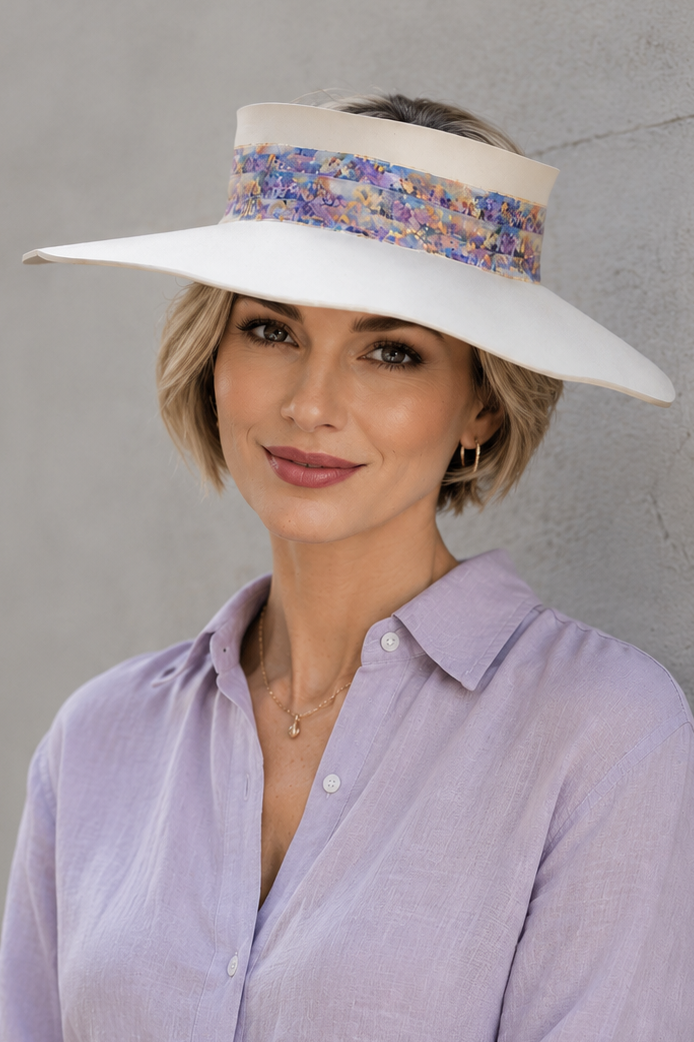 Woman wearing a wide-brimmed hat and light purple shirt against a gray wall
