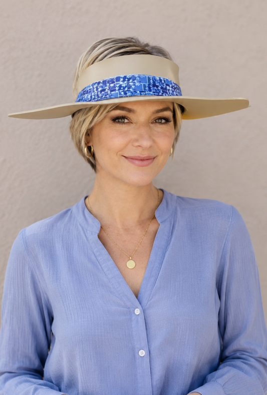 Woman wearing a wide-brimmed hat with a blue band against a beige background