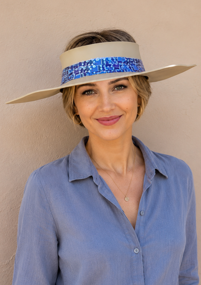 Woman wearing a blue shirt and beige visor with a blue band against a beige wall