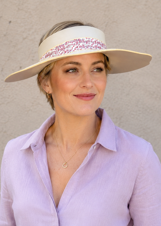 Woman wearing a light purple shirt and white visor against a plain background
