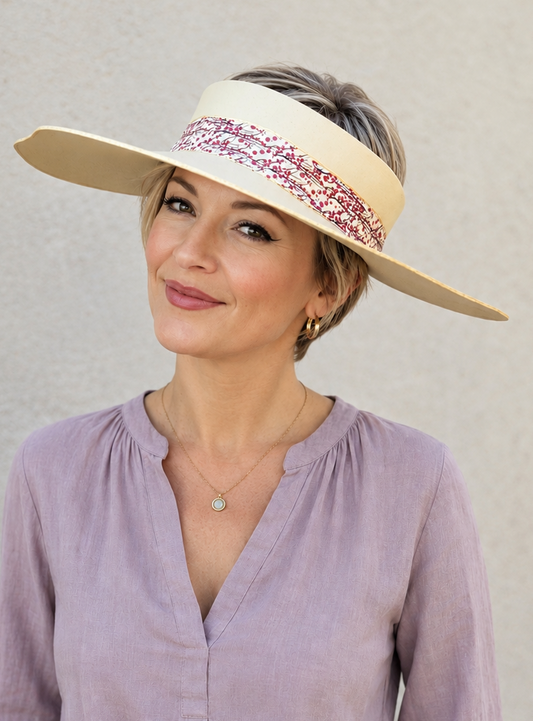 Woman wearing a wide-brimmed hat with a decorative band against a plain background