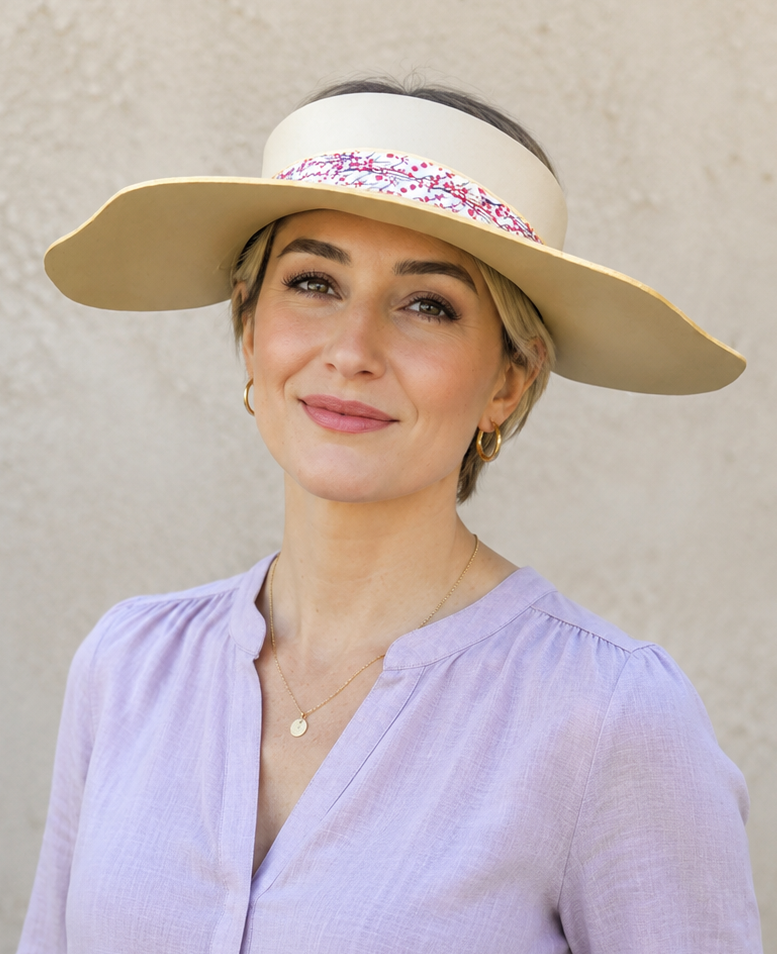 Woman wearing a wide-brimmed hat with a decorative band against a plain background