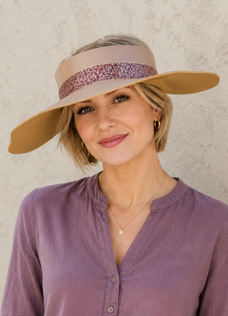 Woman wearing a wide-brimmed hat and purple shirt against a neutral background